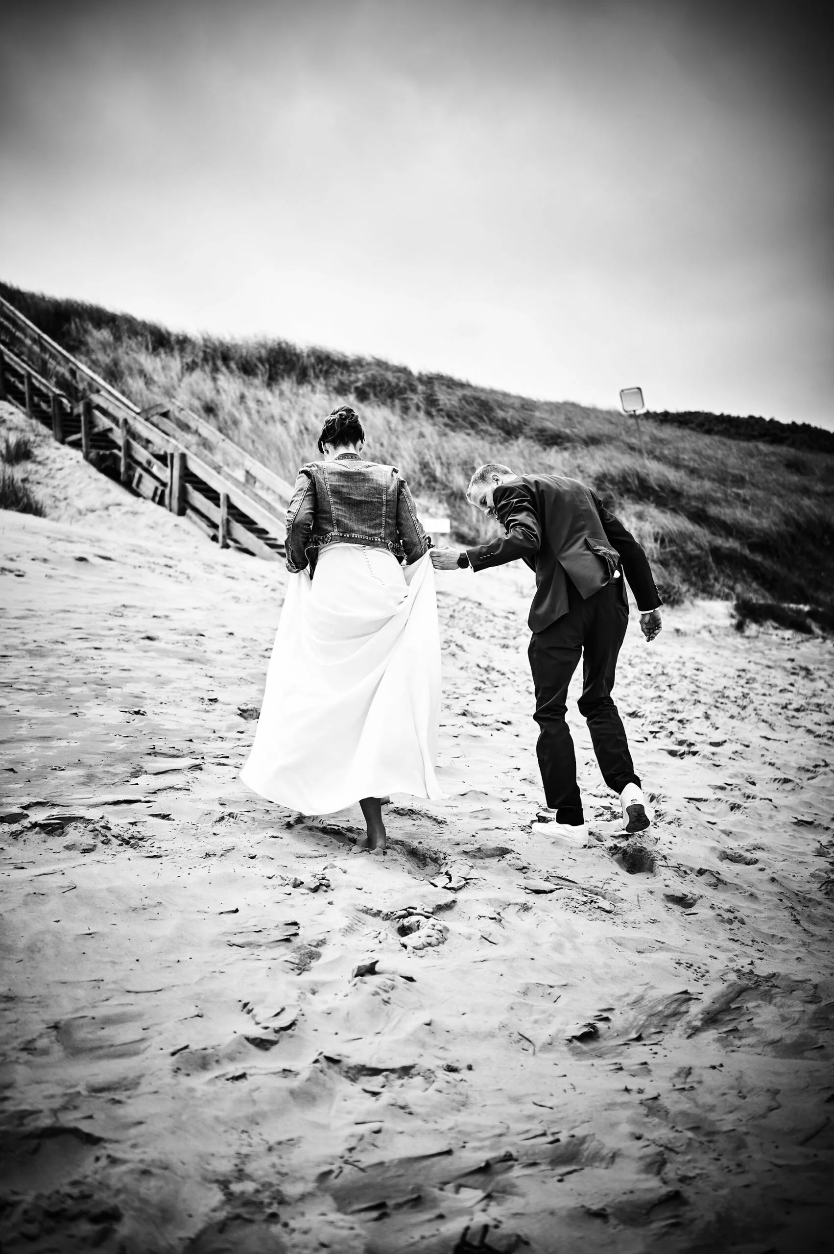 Brautpaar läuft auf Dünen zu