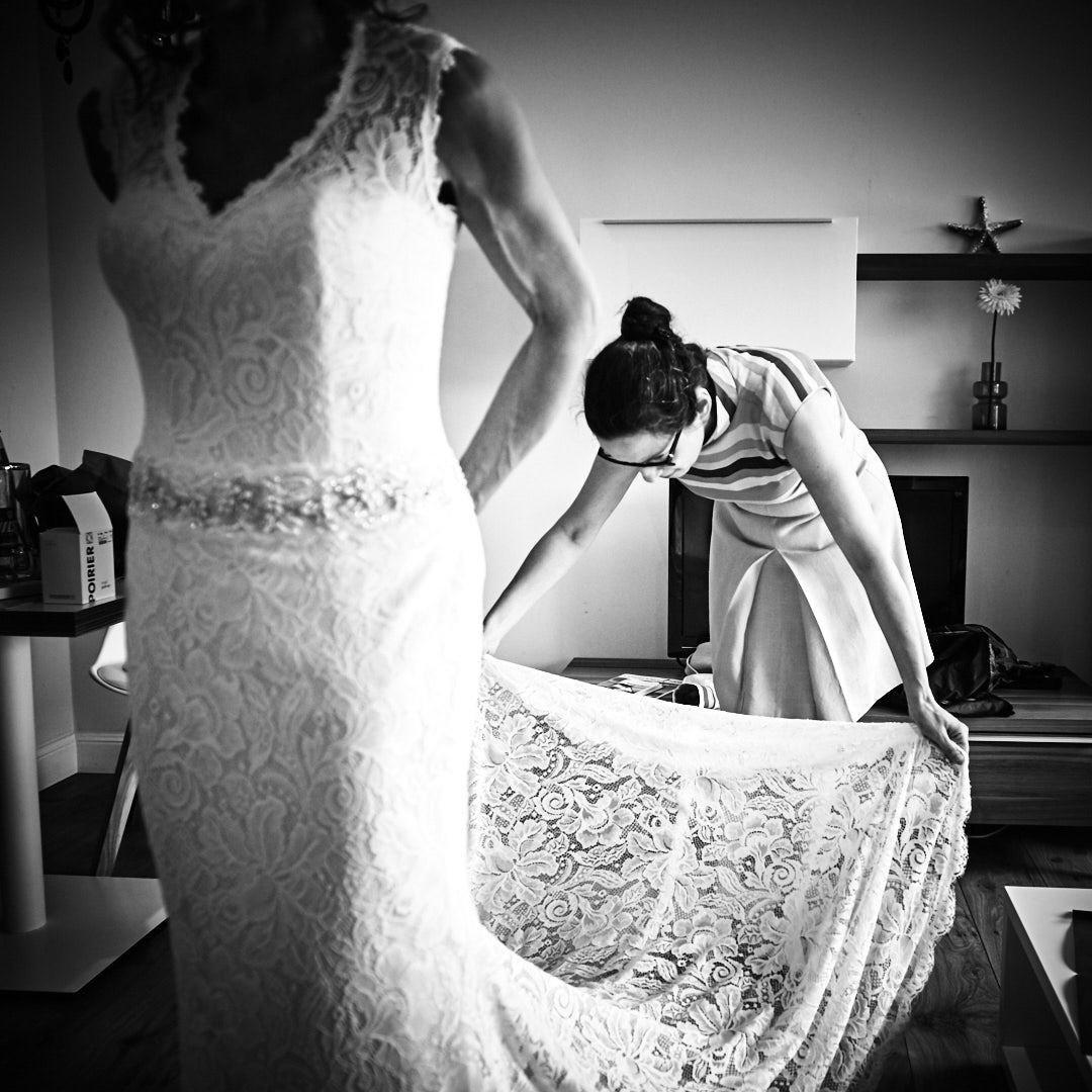 Trauzeugin richtet Kleid der Braut